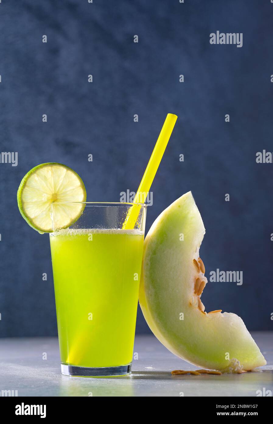 Succo di melone fresco Honeydew su sfondo blu scuro con una fetta di lime; spazio copia Foto Stock