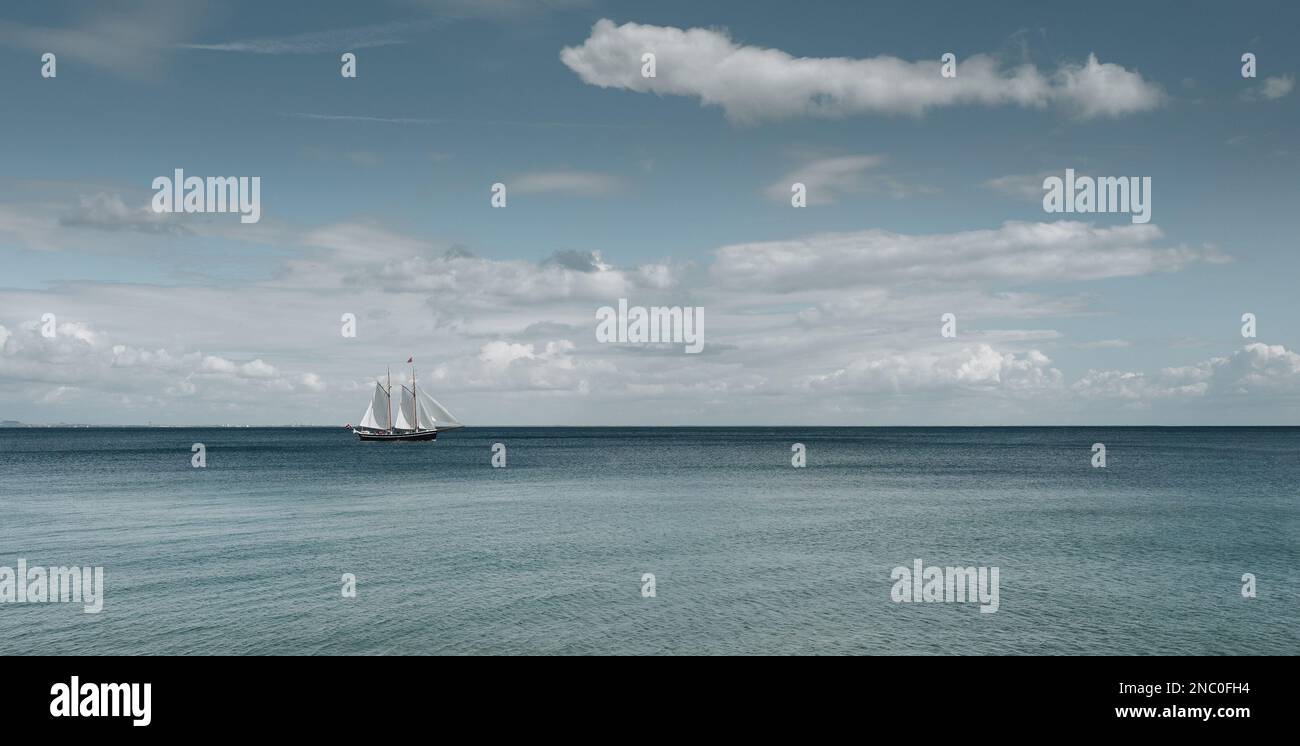 Vecchia nave alta di legno con vele bianche che attraversano l'oceano in una giornata ventosa Foto Stock