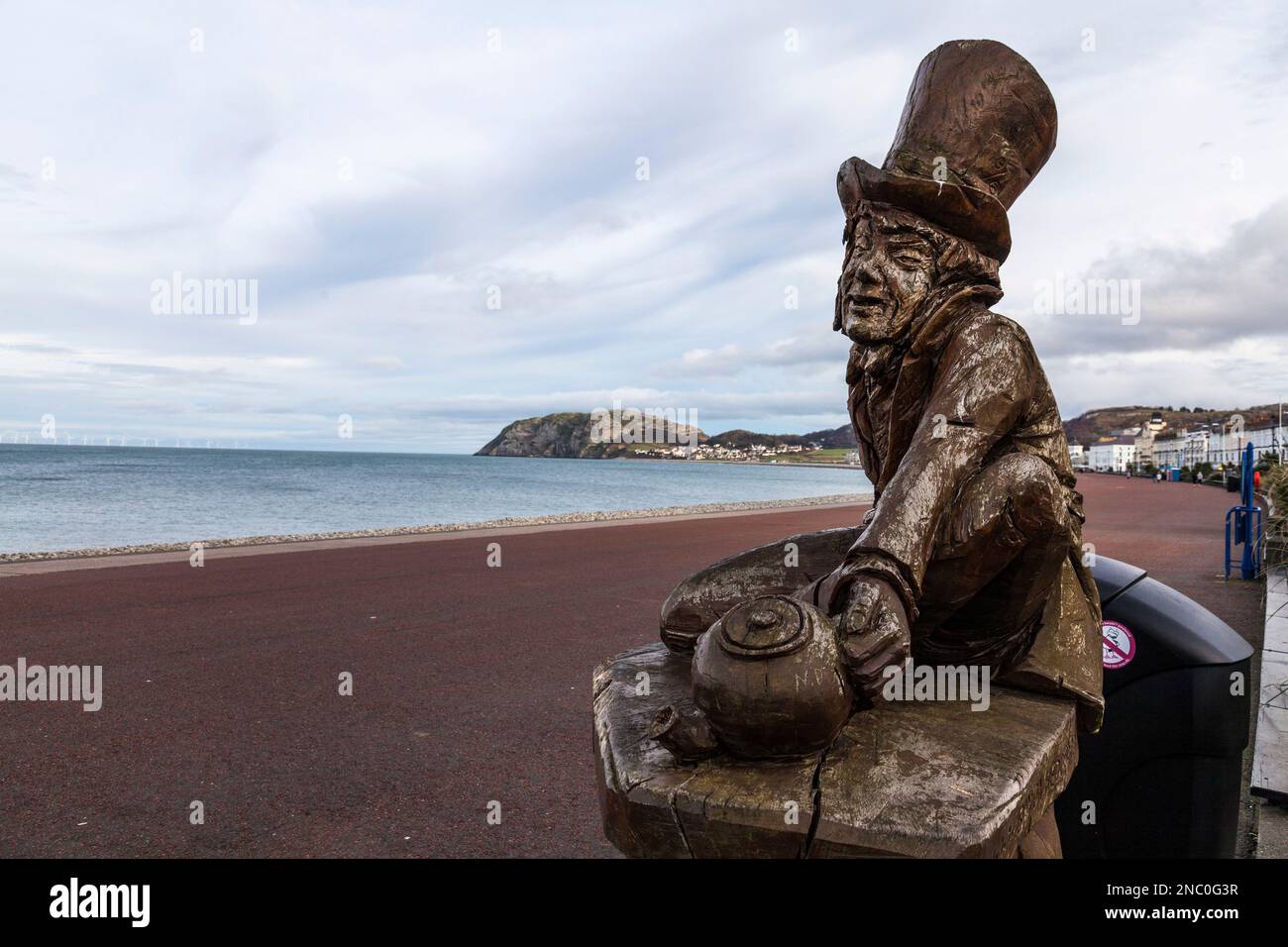 Il lungomare di Llandudno, Galles del Nord, Regno Unito con la statua in legno di Mad Hatter in primo piano e la piccola Orme sullo sfondo Foto Stock