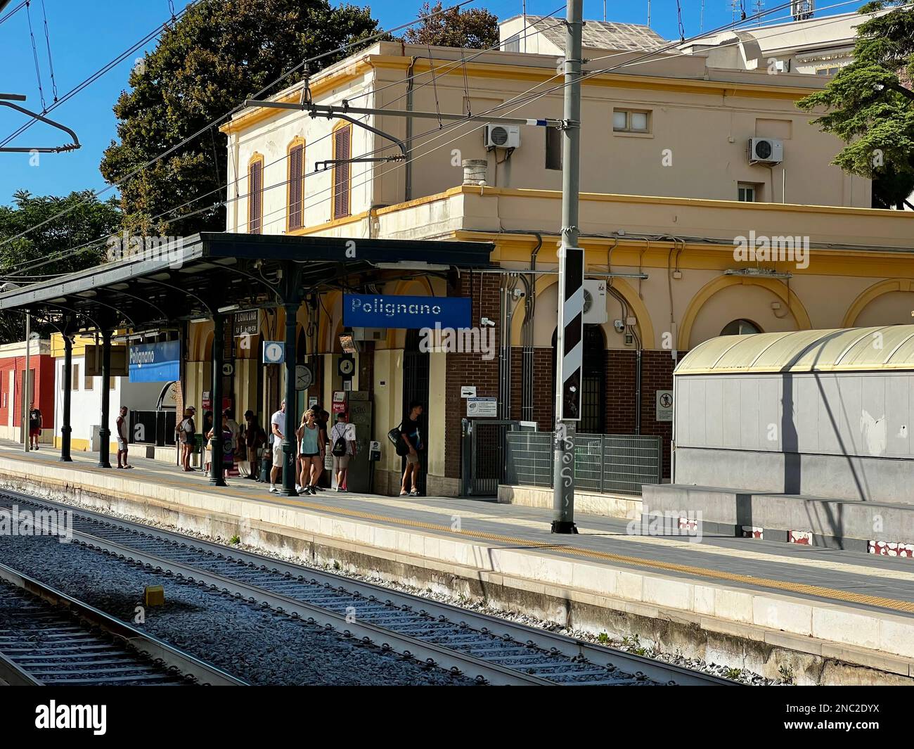 I passeggeri aspettano sotto il tetto alla stazione ferroviaria di Polignano a Mare. Foto Stock