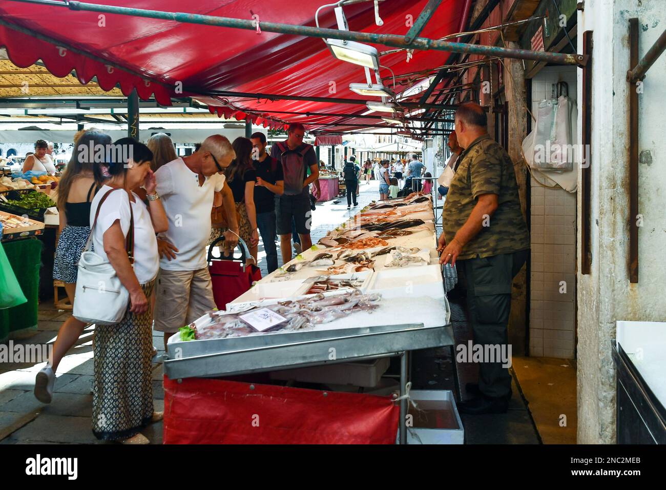 Le persone che acquistano il pescato del giorno presso una bancarella del mercato di Rialto in piazza campo della Pescaria, sestiere di San Polo, Venezia, Veneto, Italia Foto Stock