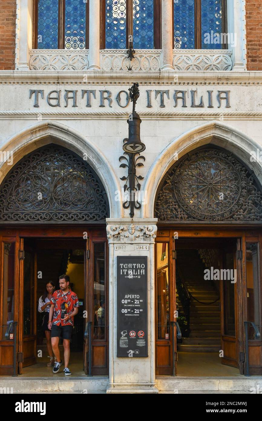Coppia di turisti che lasciano l'edificio neogotico del Teatro Italia, oggi trasformato in un supermercato, sestiere di Cannaregio, Venezia, Italia Foto Stock