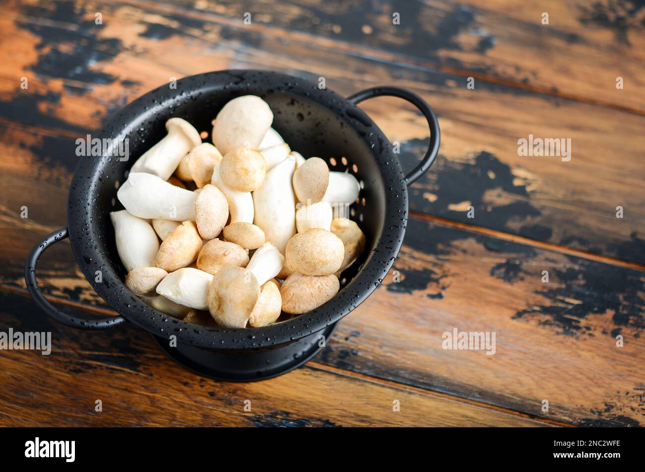 Funghi Eringi o Re Trumpet freschi crudi su un tavolo di legno. Foto Stock