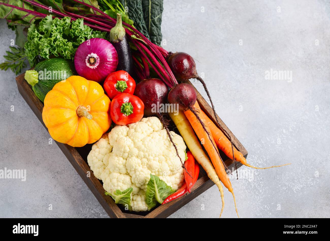 Verdure biologiche fresche in scatola di legno su fondo grigio cemento. Foto Stock