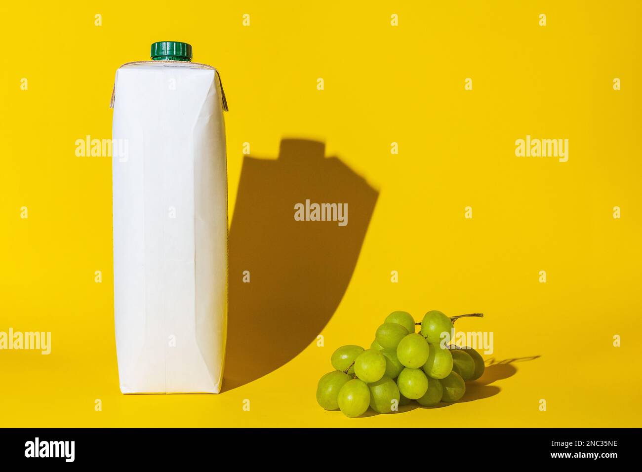 confezione succo vuoto copia spazio uva, succo d'uva per bere, diversi oggetti, ombra dura, bianco cartone uva di colore verde, giacciono sulla superficie del Foto Stock