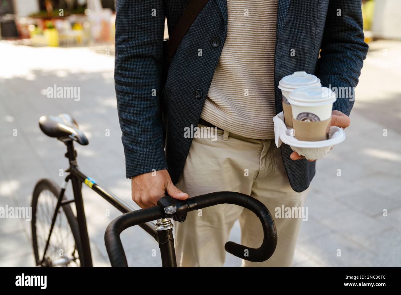 Zenzero europeo che indossa una giacca a piedi con bicicletta e caffè in strada cittadina Foto Stock