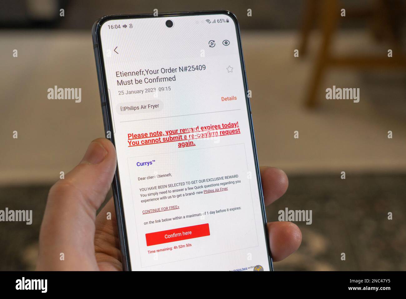 Una mano che tiene in mano uno smartphone con un falso messaggio di phishing Currys da parte di truffatori, Inghilterra. Concetto: E-mail fraudolente, e-mail fraudolente, e-mail truffa, frodi nel Regno Unito Foto Stock