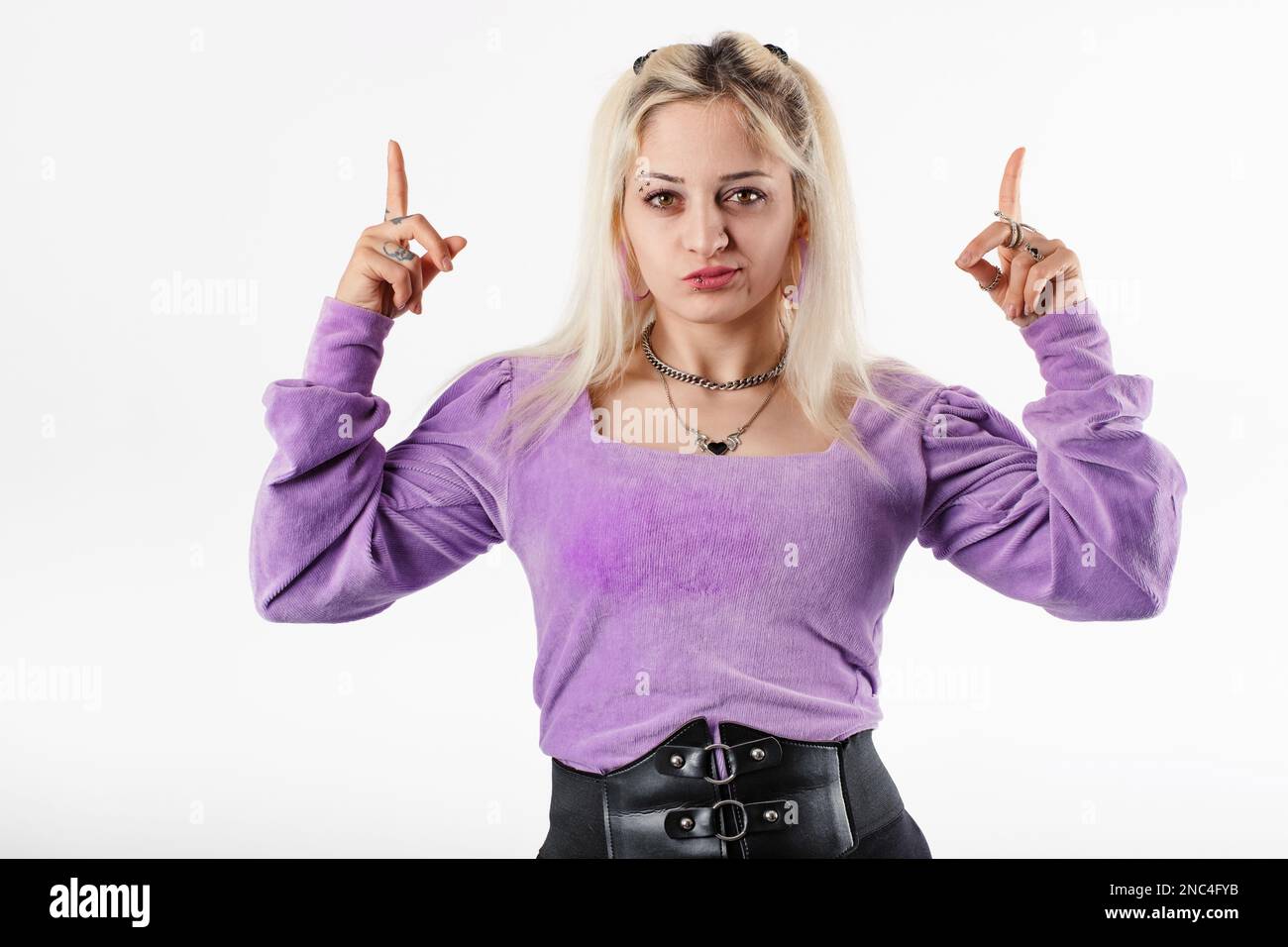 Donna millennial carina che indossa blusa in piedi isolato su sfondo bianco con un'espressione insoddisfatta, punta verso l'alto con due dita. Foto Stock