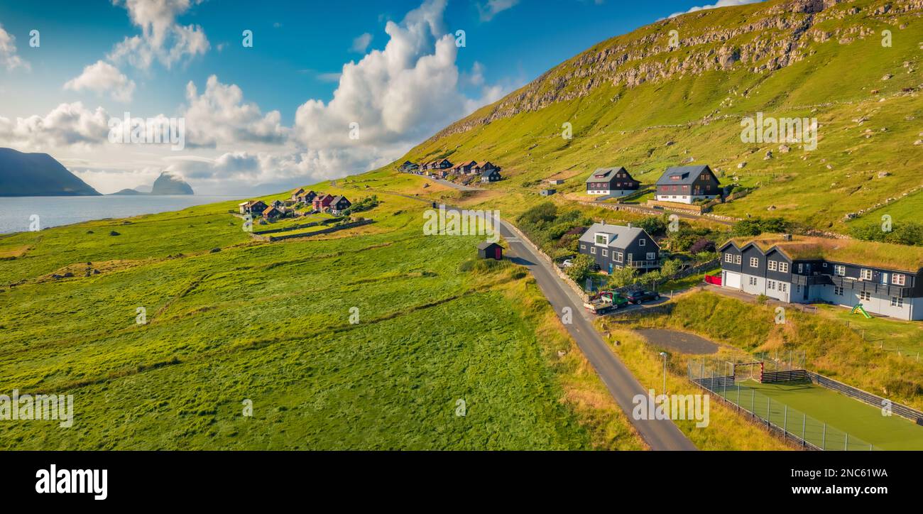 Soleggiata vista estiva dal drono volante del villaggio di Kirkjubour con Hestur Island sullo sfondo. Panorama mattutino delle Isole Faroe, Danimarca, Europa. Foto Stock