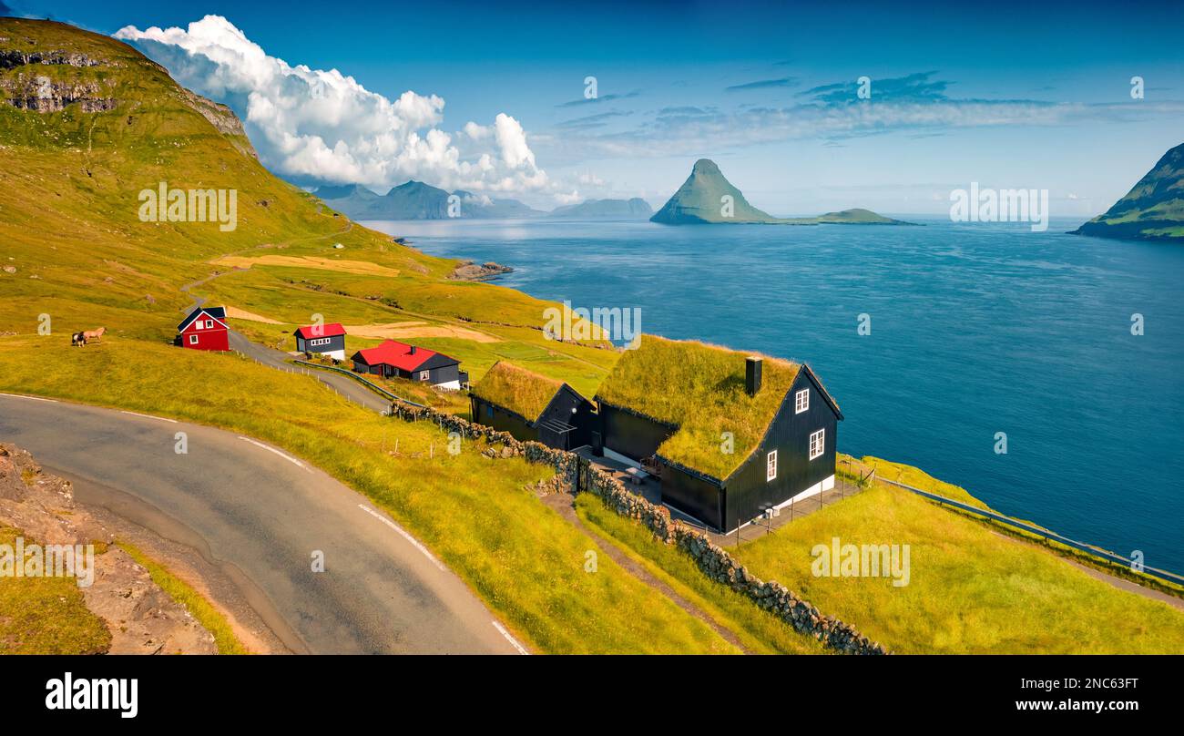 Colorata vista estiva dal drone volante del villaggio di Velbastadur con tipiche case in cima al prato. Esotica scena mattutina dell'isola di Streymoy, Faroe, Danimarca, e Foto Stock