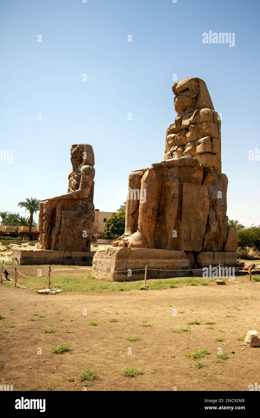 Luxor, Egitto. I Colossi di Memnon sono due massicce statue in pietra del faraone Amenhotep III, che si trovano di fronte al tempio mortuario rovinato Foto Stock