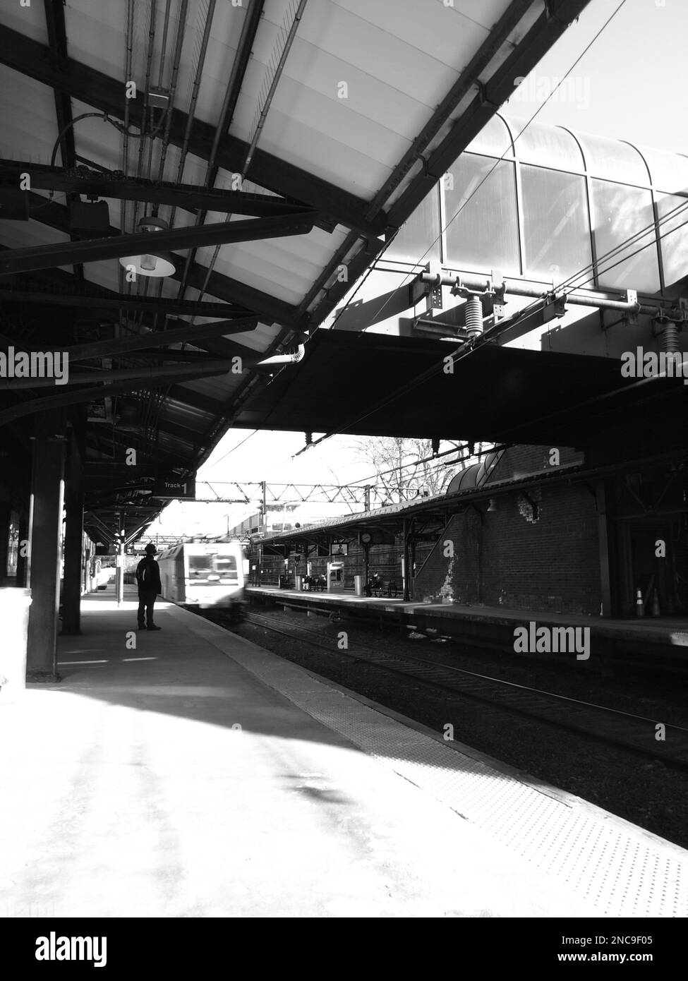 Figura oscura in attesa di un treno alla stazione Summit, New Jersey a Summit, New Jersey. Treno in avvicinamento in bianco e nero. Foto Stock
