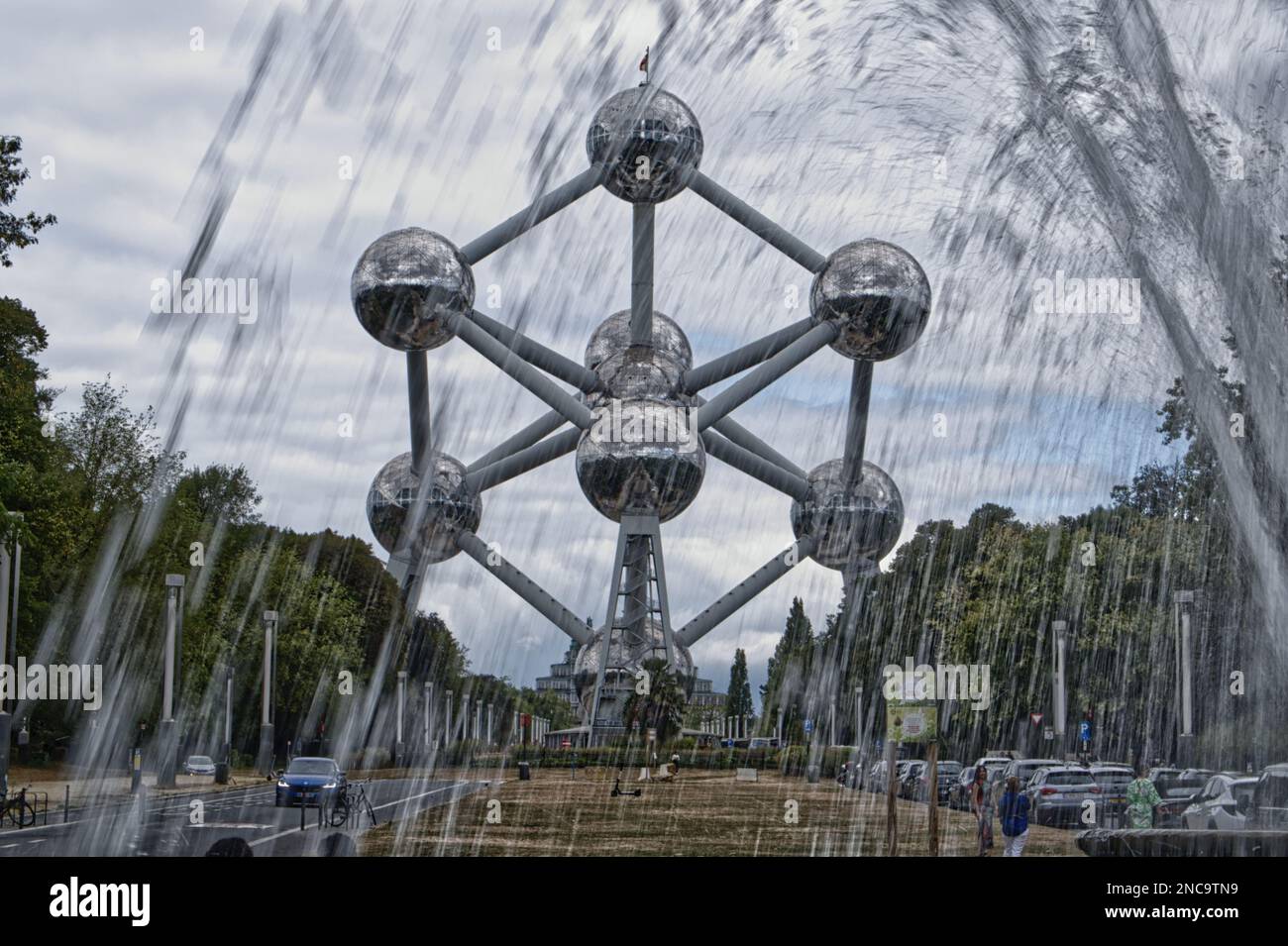 Monumento dell'Atomium, con una fontana in primo piano. Scattato contro un cielo nuvoloso. Bruxelles, Belgio.. Foto Stock
