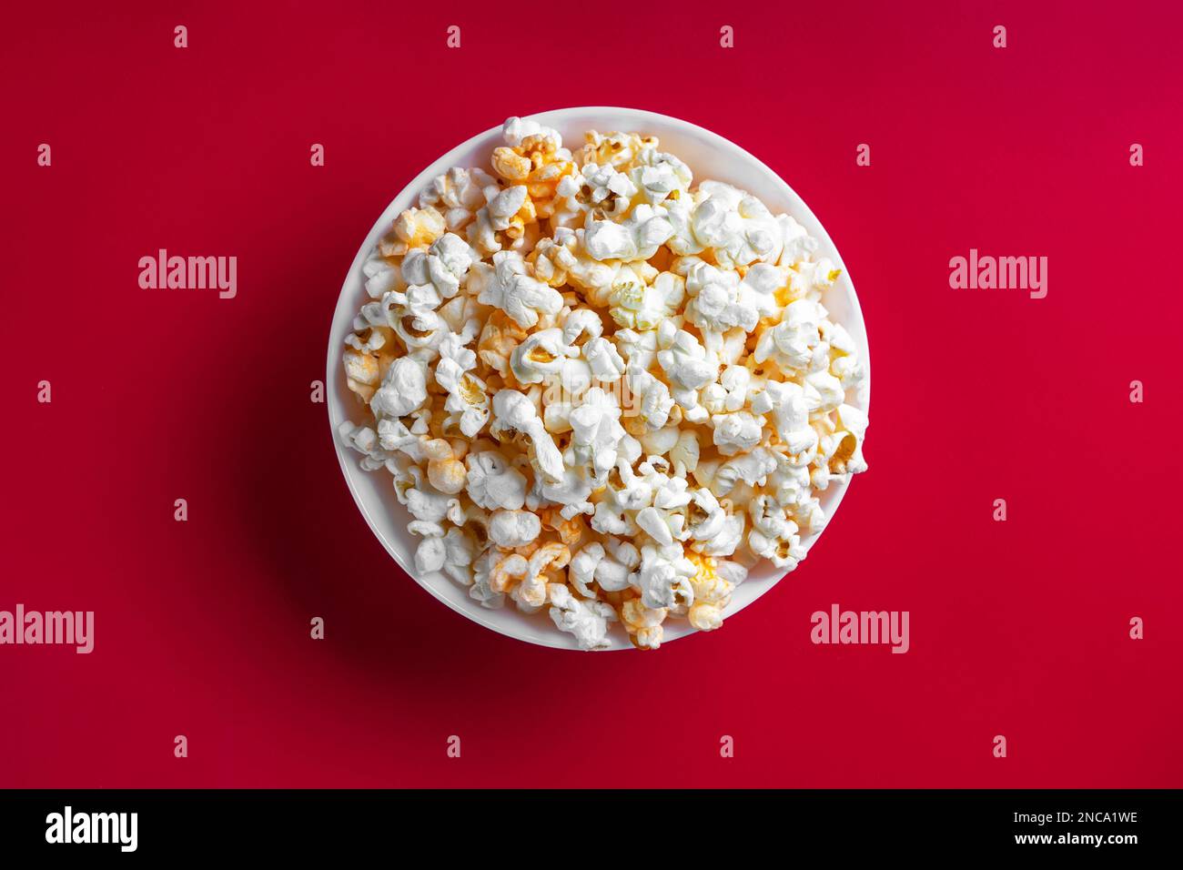 Gustoso popcorn formaggio in ciotola isolato su sfondo rosso. Vista dall'alto, disposizione piatta. Fast food, film, cinema e intrattenimento. Foto Stock