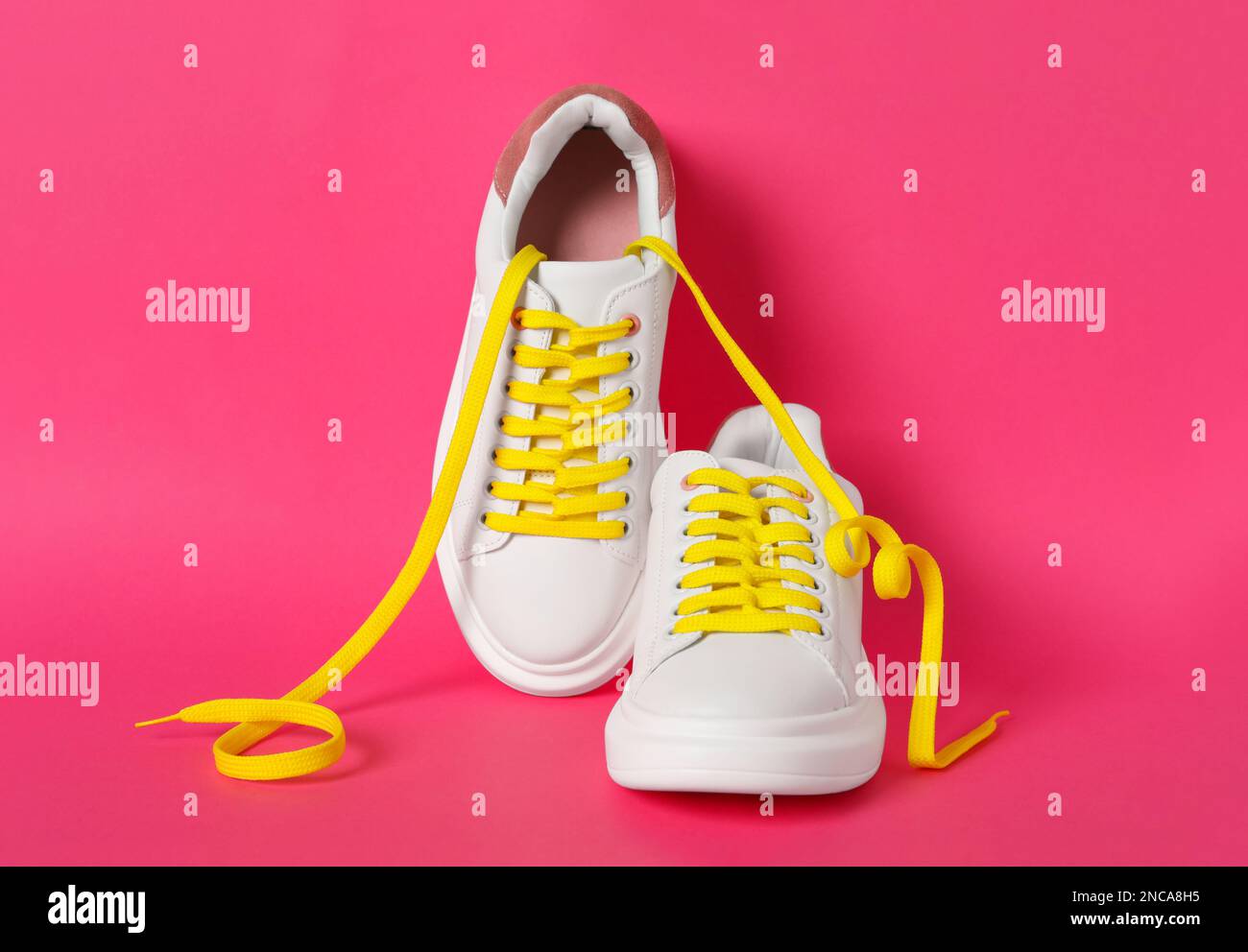 Paio di scarpe eleganti con lacci gialli su sfondo rosa Foto Stock