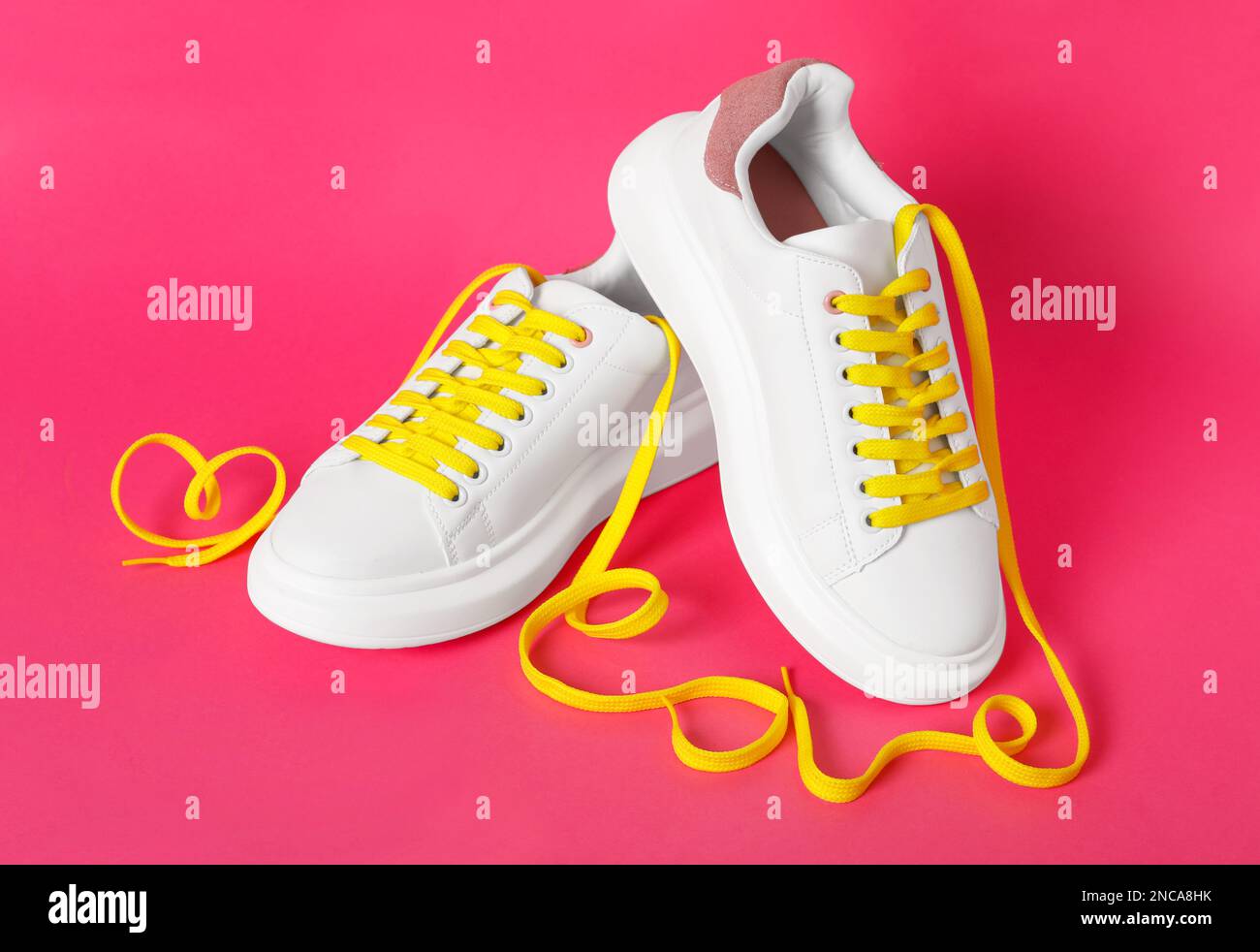 Paio di scarpe eleganti con lacci gialli su sfondo rosa Foto Stock