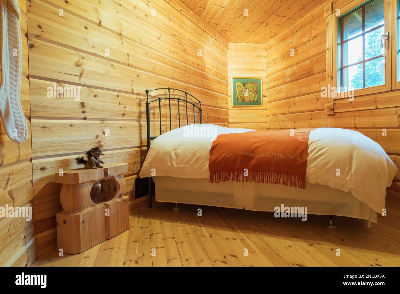 Letto queen size con testiera in metallo antico, copriletto bianco e letto rosso nella camera da letto di forma irregolare all'interno di una casa in legno di pino scozzese. Foto Stock