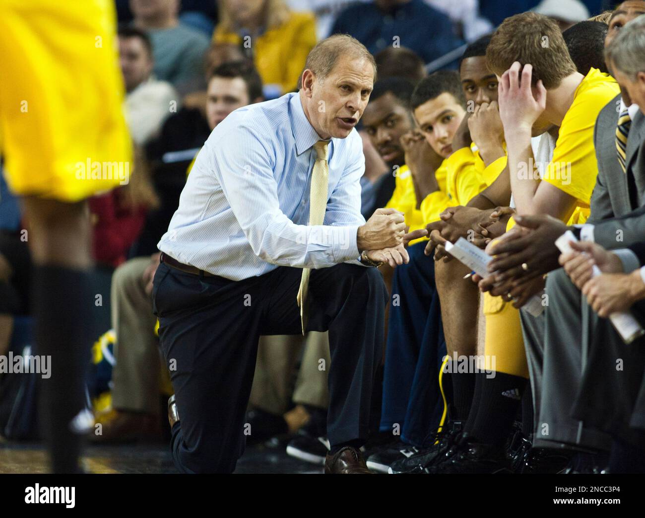 FILE - In this Dec. 28, 2010, file photo, Michigan head coach John Beilein kneels to speak with his bench players during a free throw break in the second half of an NCAA college basketball game against Purdue at Crisler Arena in Ann Arbor, Mich. Young players are supposed to have trouble picking up coach Beilein's complex offense, but it's Michigan's defense that's given the Wolverines problems lately. (AP Photo/Tony Ding, File) Foto Stock