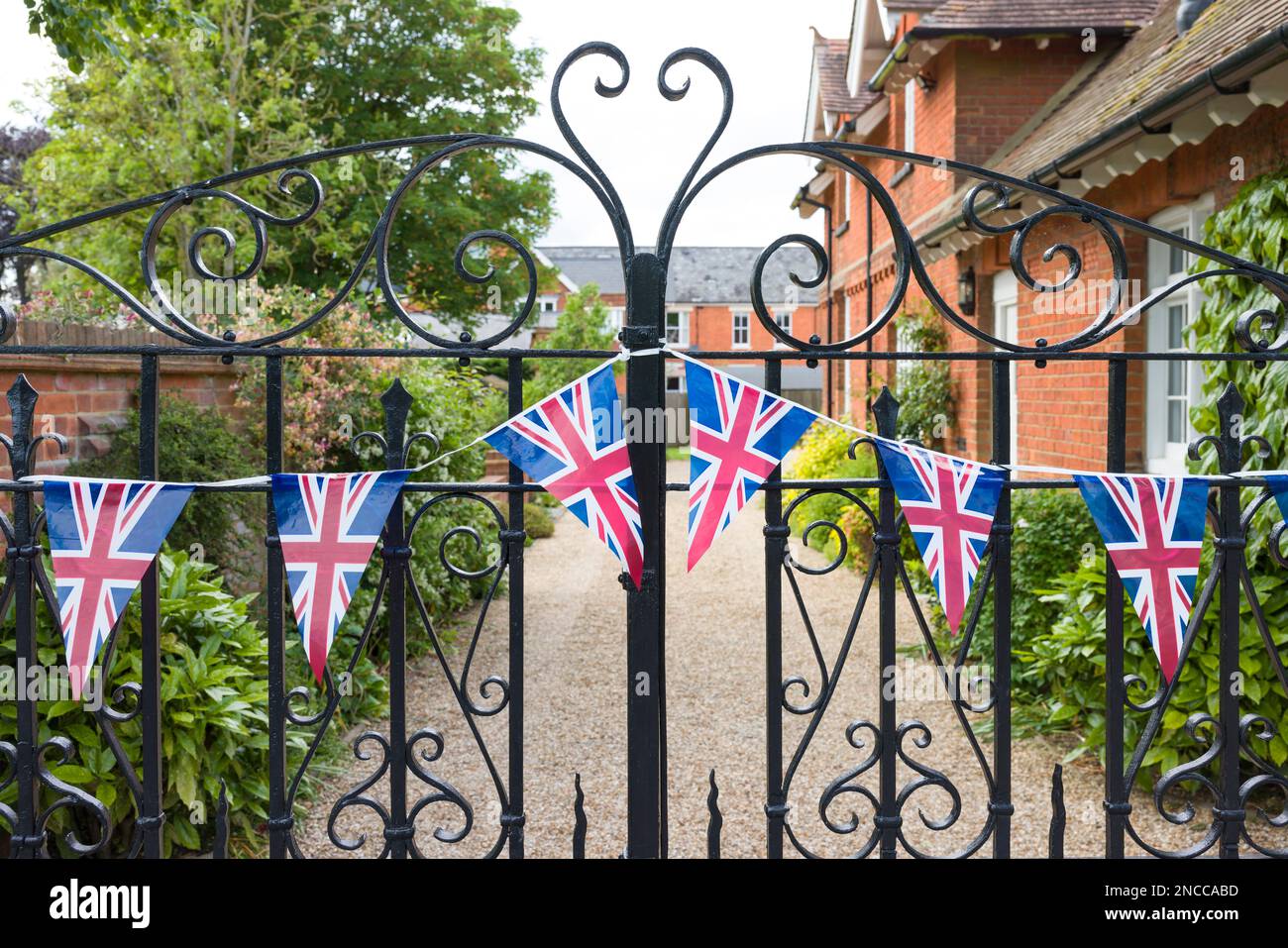 Union Jack (bandiera dell'Unione) accatastandosi fuori dai cancelli di ferro di una casa di campagna tradizionale nel Buckinghamshire, Inghilterra, Regno Unito Foto Stock