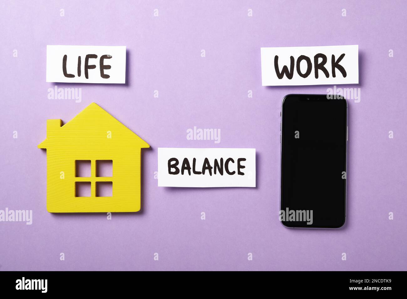 Casa di legno, smartphone e parole vita, equilibrio, lavoro su sfondo viola, piatto Foto Stock