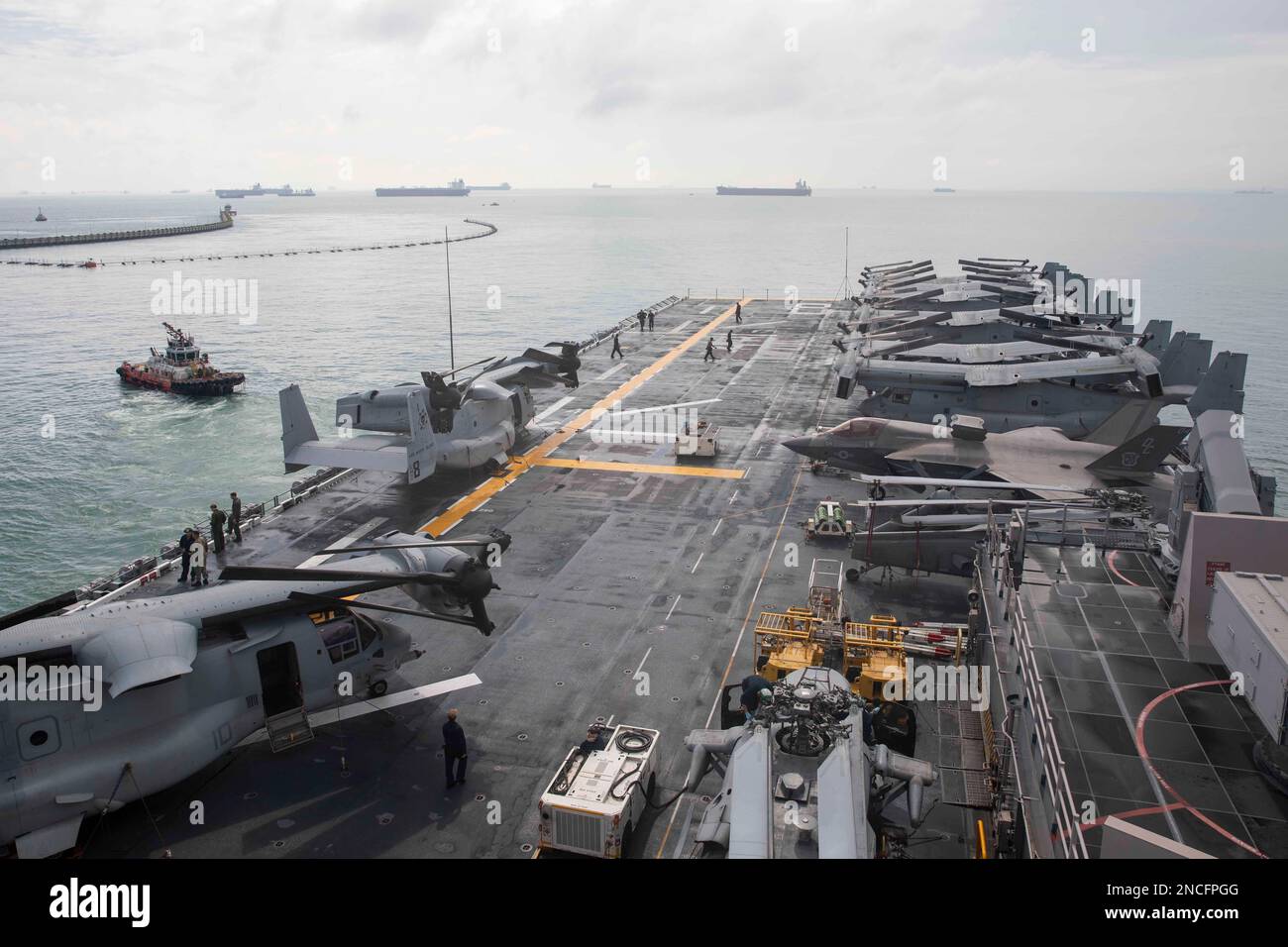 230210-N-YR119-1013 Un rimorchiatore guida la nave d'assalto anfibio USS Makin Island (LHD 8) lontano dal molo durante le manovre ristrette, il 10 febbraio 2023 nello stretto di Singapore. Le barche di rimorchiatore assistono le navi principali guidandole in modo sicuro da e verso il molo e assicurandosi che non vengano ferite durante il transito. Il Makin Island Amphibious Ready Group, composto da nave d'assalto anfibio USS Makin Island (LHD 8) e bacini di trasporto anfibio USS Anchorage (LPD 23) e USS John P. Murtha (LPD 26), opera nell'area di operazioni della flotta degli Stati Uniti 7th con l'unità marittima di spedizione imbarcata 13th Foto Stock