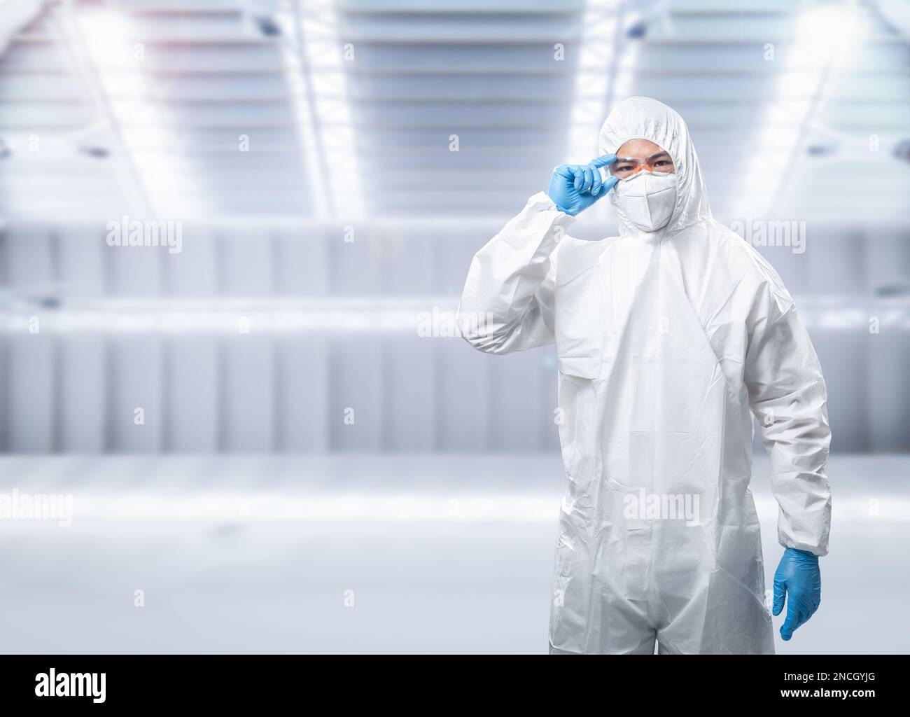 Il lavoratore indossa un tuta di protezione medica o un tuta bianca con maschera e occhiali di protezione Foto Stock