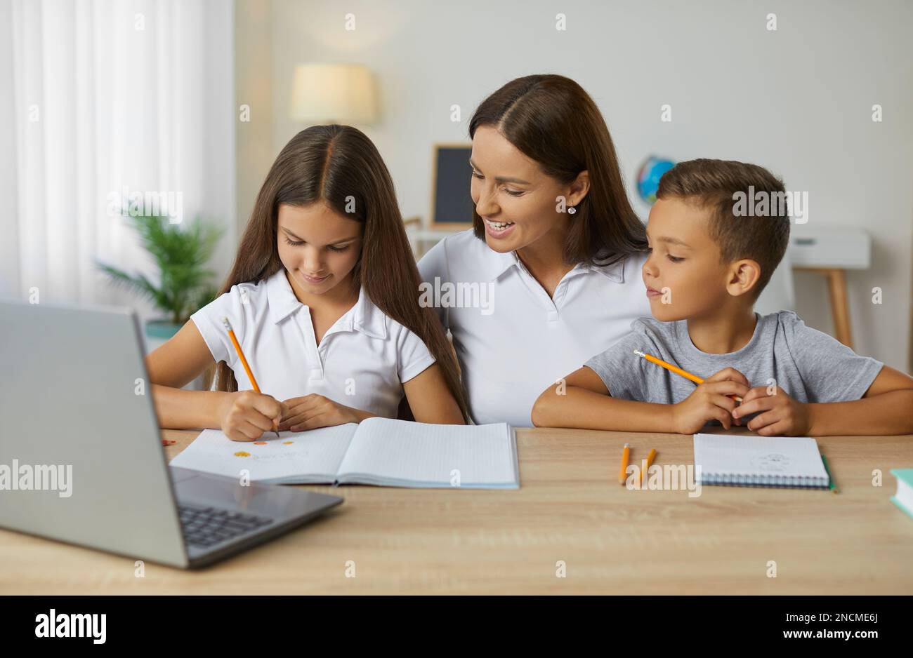 Madre, sorella e fratello stanno facendo i compiti a casa. Foto Stock