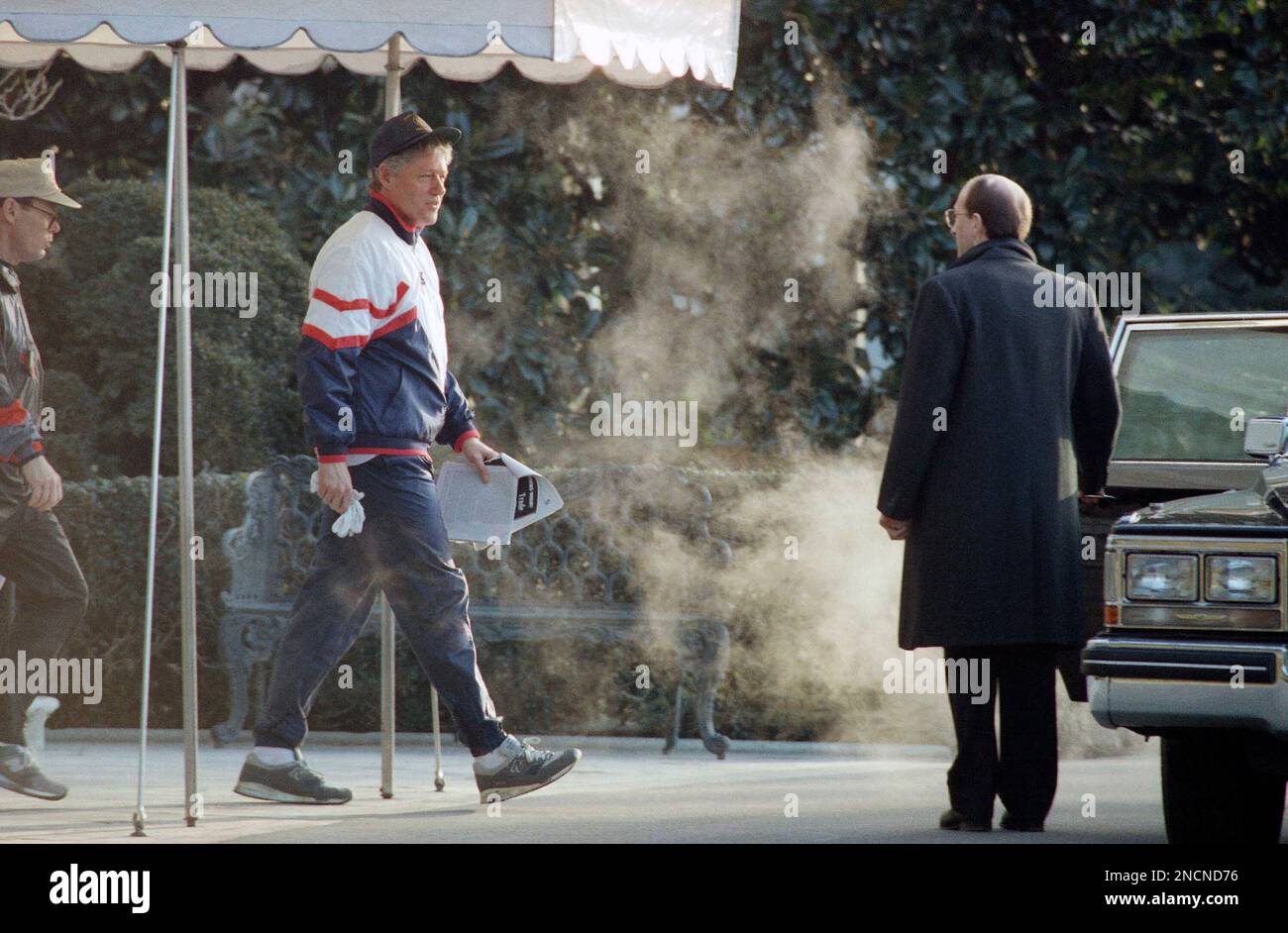 President Bill Clinton walks through exhaust steam from a waiting car
