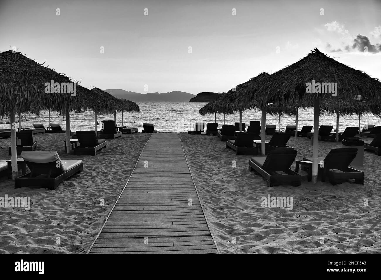 Vista di un sentiero in legno che conduce alla splendida spiaggia di Mylopotas in Grecia iOS al tramonto in bianco e nero Foto Stock