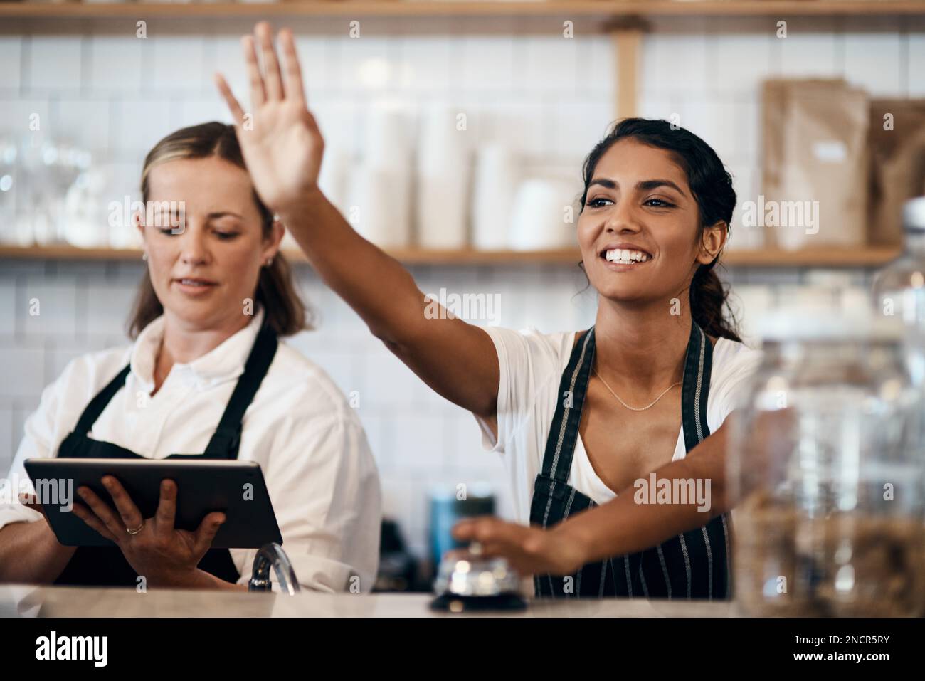 Numero d'ordine 105, si accende. una giovane donna suona il campanello di servizio mentre lavora in un bar. Foto Stock