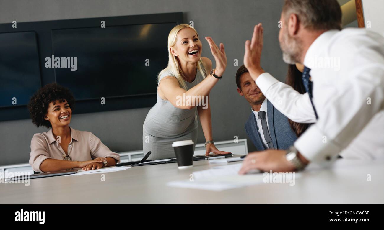 Due professionisti di affari che si accaniscono a vicenda per celebrare il loro successo e il lavoro di squadra. Gruppo di uomini d'affari felici che hanno una riunione in un b Foto Stock