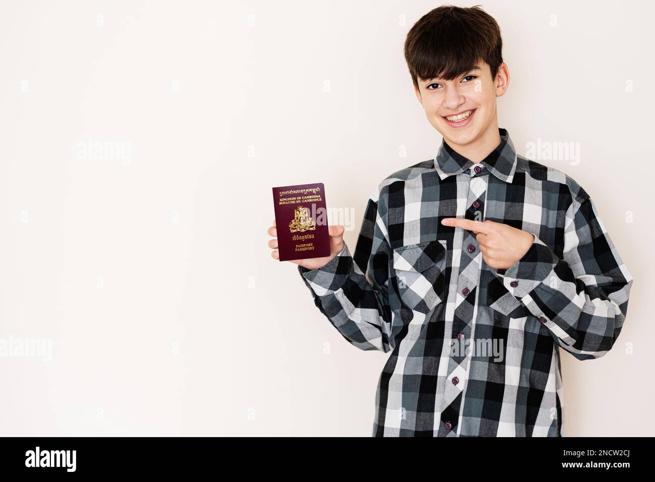 Ragazzo giovane adolescente con passaporto Cambogia guardando positivo e felice in piedi e sorridente con un sorriso fiducioso su sfondo bianco. Foto Stock