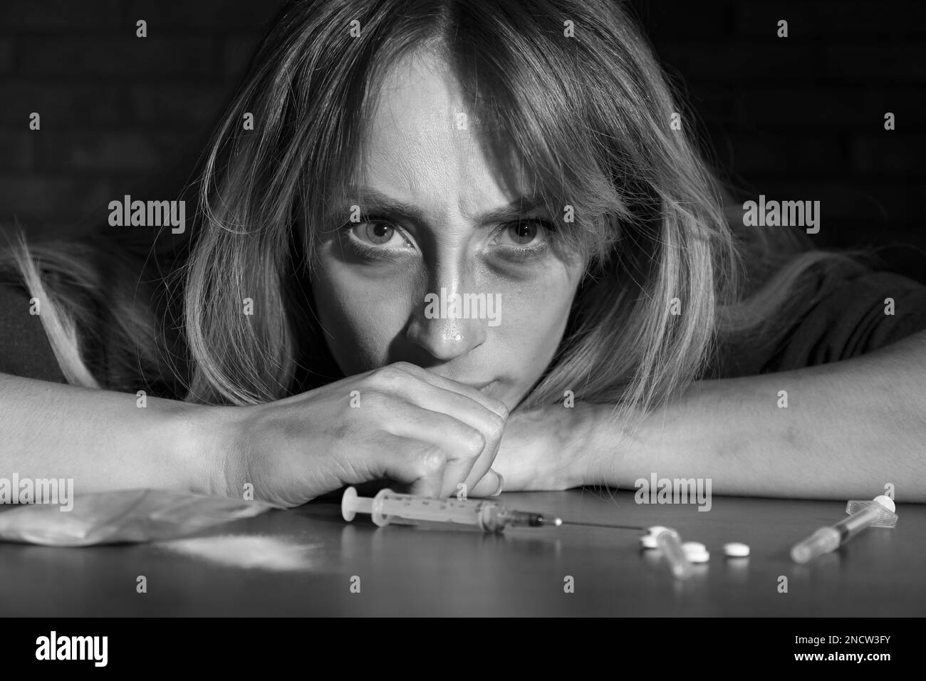 Donna addicted al tavolo con le droghe differenti, effetto bianco e nero Foto Stock