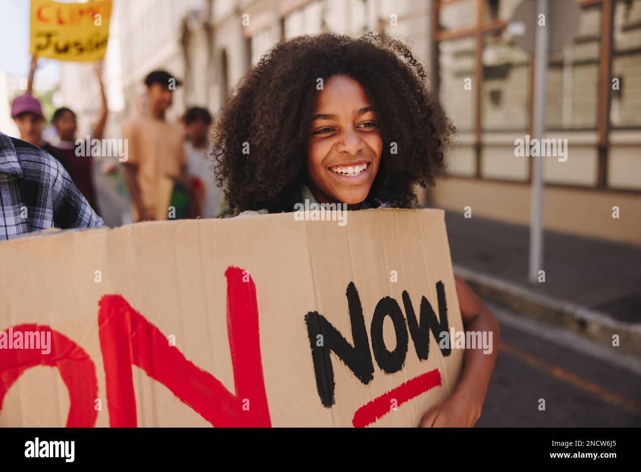 Ragazza felice sorridente allegra mentre marciava contro il cambiamento climatico con un gruppo di manifestanti. Attivisti giovanili che si battono per la giustizia climatica Foto Stock