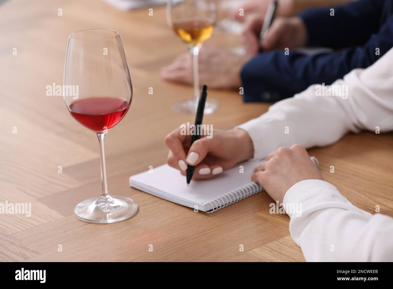 Sommelier prendere appunti durante la degustazione di vini al tavolo al coperto, primo piano Foto Stock