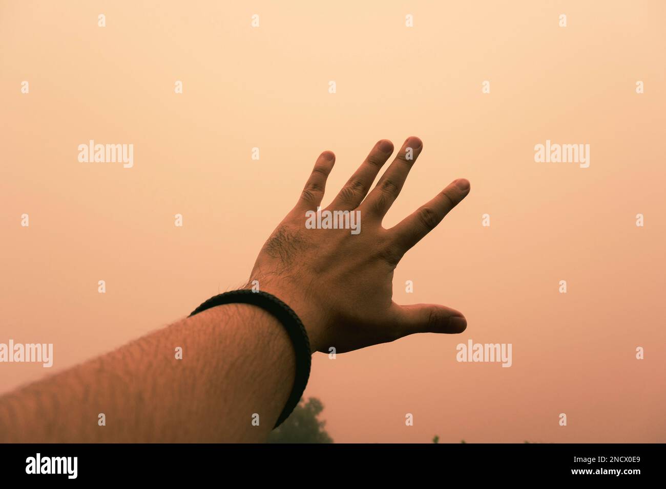 Una mano e una nebbia arancione sullo sfondo Foto Stock
