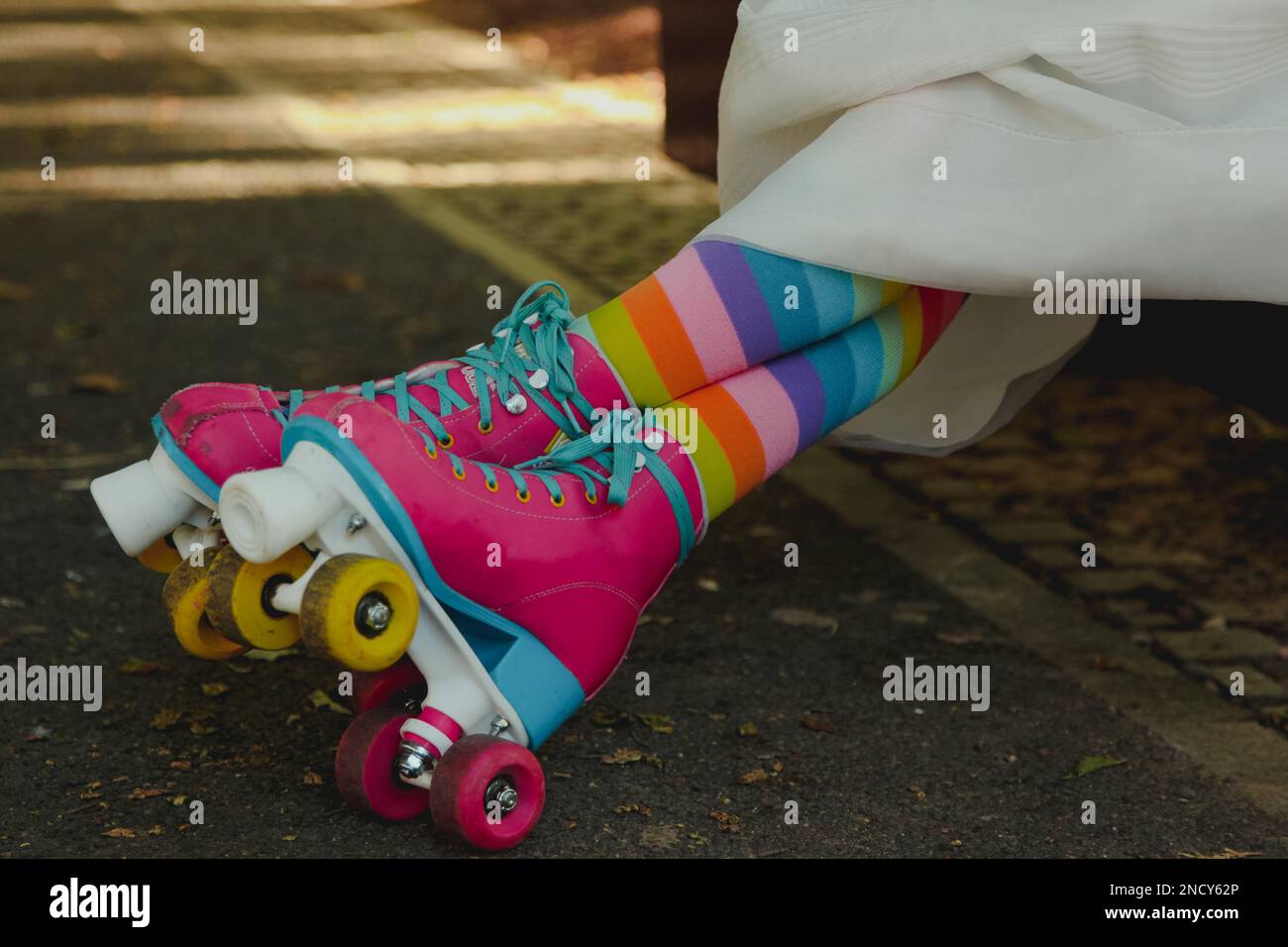 Primo piano di una donna in un abito da sposa che indossa calze lunghe multicolore e rollerskates Foto Stock