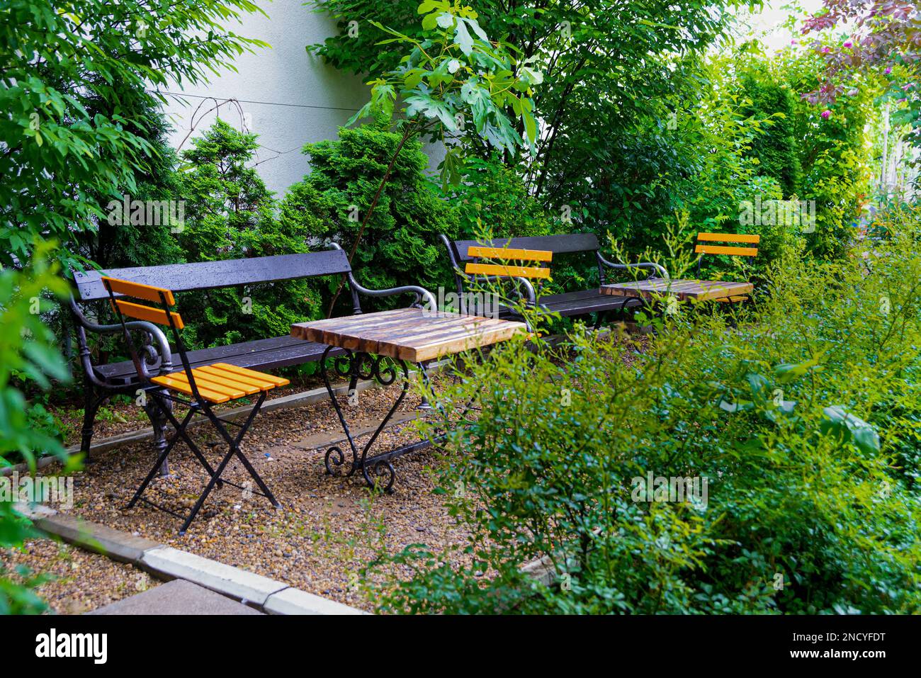 Incantevole giardino con sedie arancioni e splendidi fiori Foto Stock