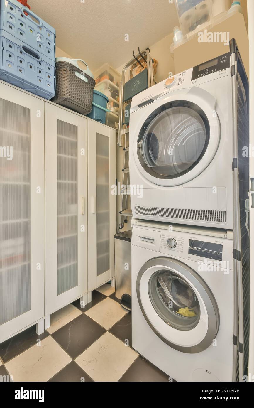 Interno della lavanderia con lavatrice e asciugatrice moderna impilata  vicino armadio con cestini di plastica sulla parte superiore Foto stock -  Alamy