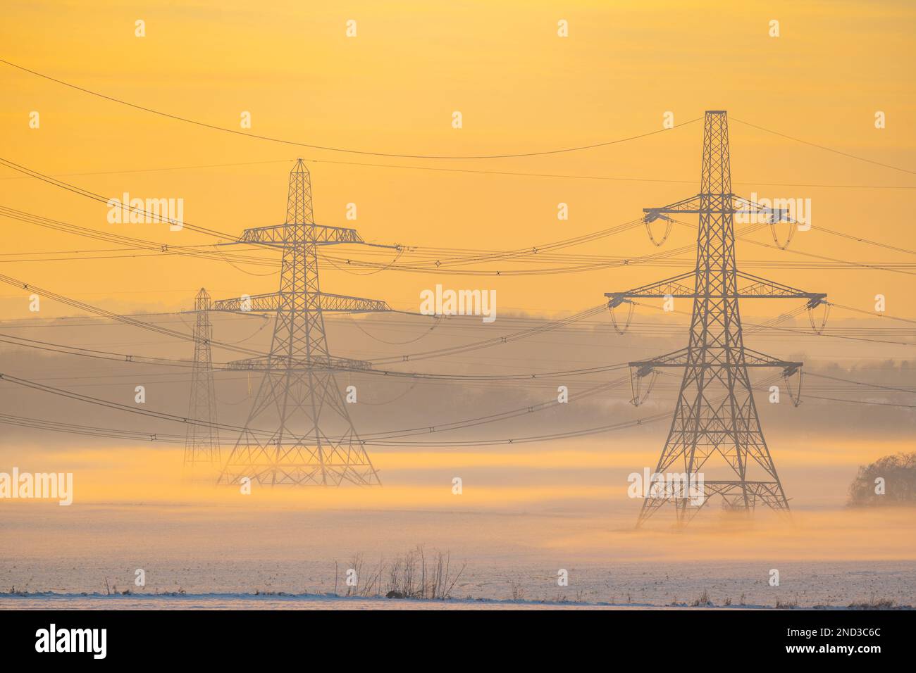 Linee elettriche sopra i campi innevati al tramonto vicino a Ifield, Gravesend Kent Foto Stock