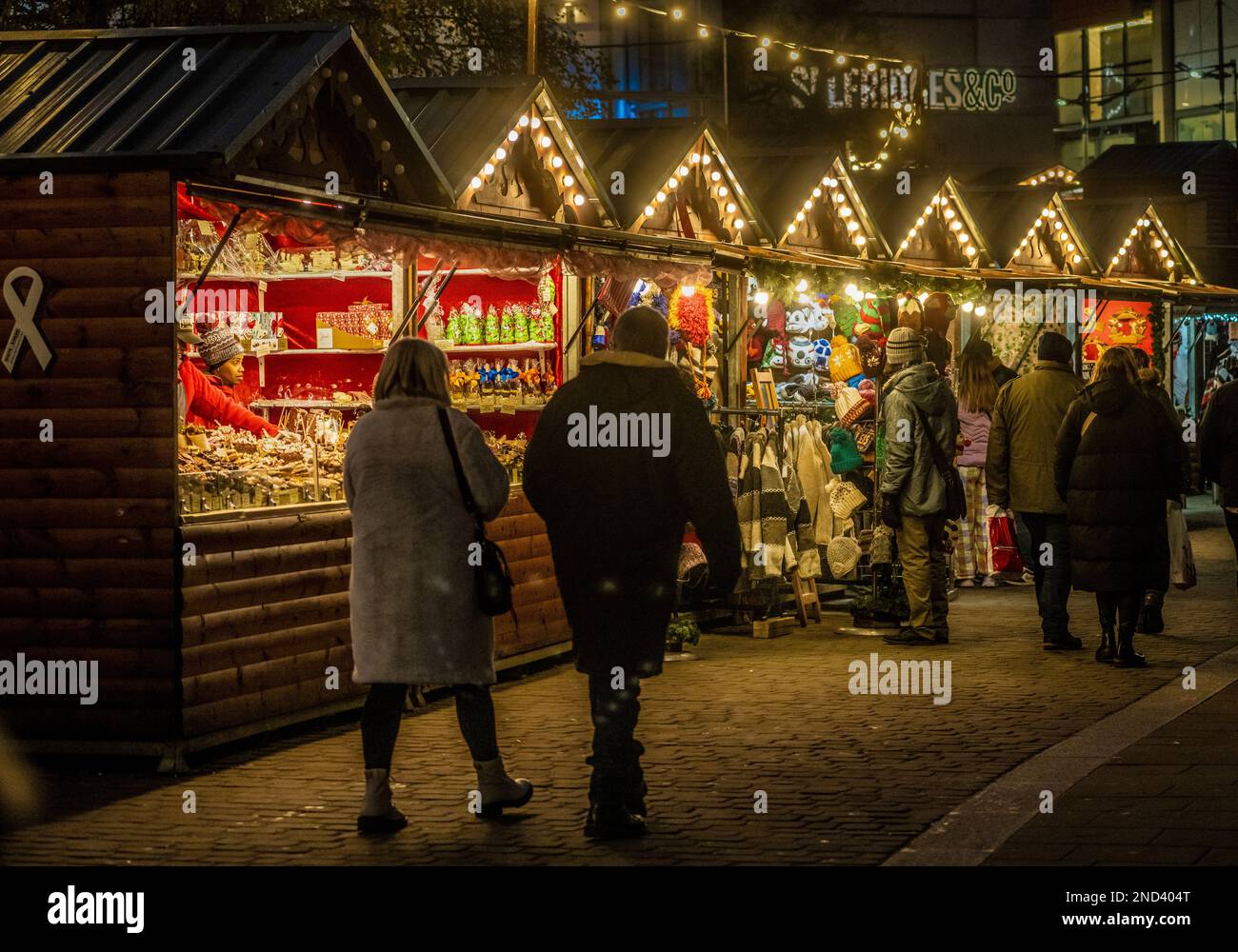 Bancarelle in legno tipo chalet alpino di fronte a Selfridges in Piazza dello scambiatore di notte. Mercatini di Natale di Manchester. Manchester. REGNO UNITO Foto Stock