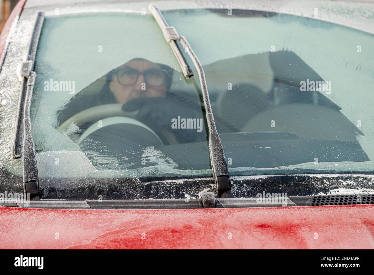 Primo piano di un parabrezza di un'auto congelata parzialmente svuotato con un conducente maschio seduto all'interno. REGNO UNITO Foto Stock