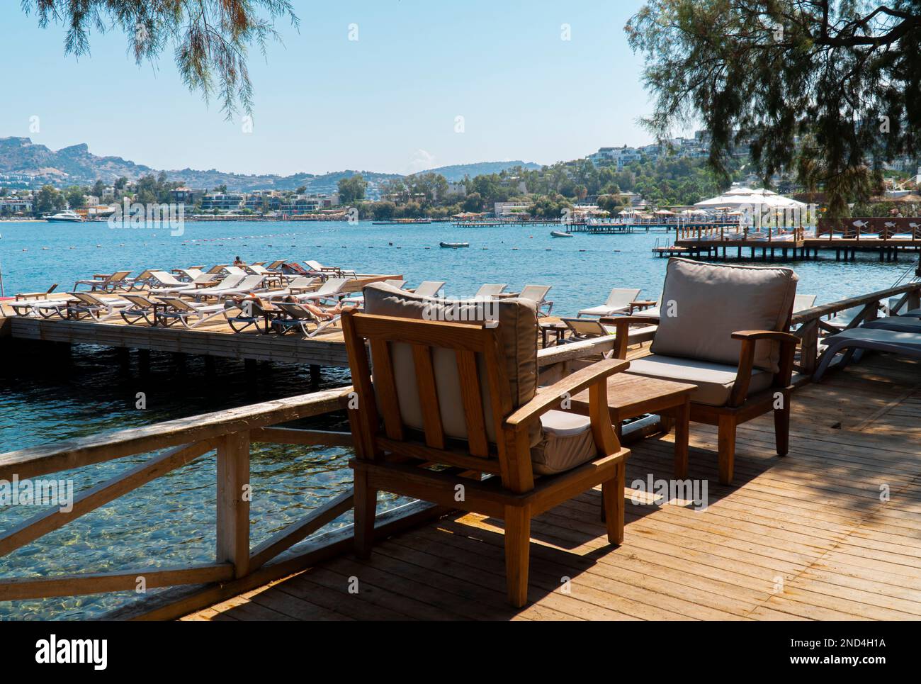 Vista del Beach club con tavoli, sedie e lettini in legno sullo sfondo, vicino al mare di Bodrum, Turchia. messa a fuoco selettiva Foto Stock
