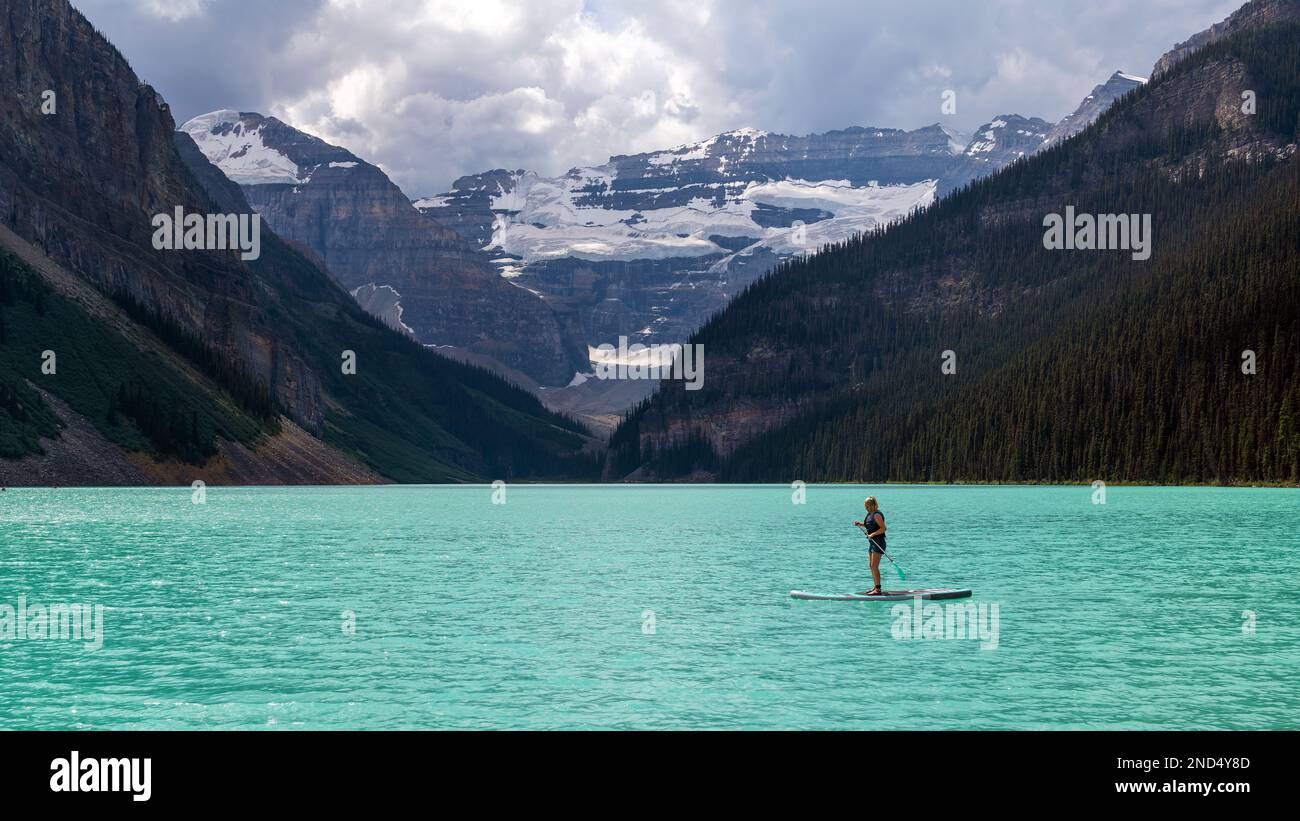 Giovane donna canadese che fa stand up paddleboarding sul lago Louise all'interno del parco nazionale di Banff, Canada. Foto Stock