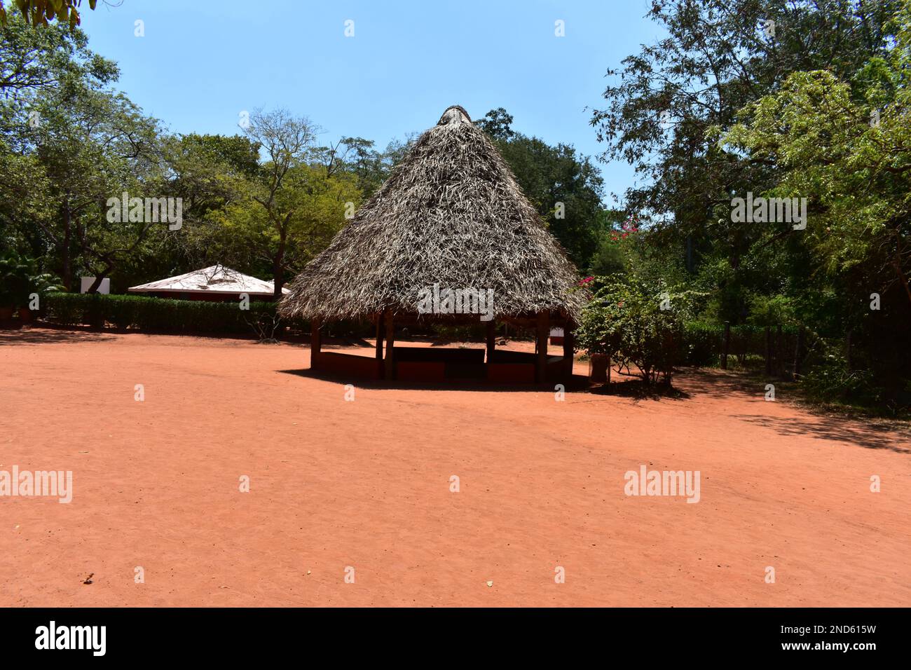 Una piccola capanna a Pondicherry, in India, composta da legno ed erba, con sabbia rossa in primo piano. Foto Stock