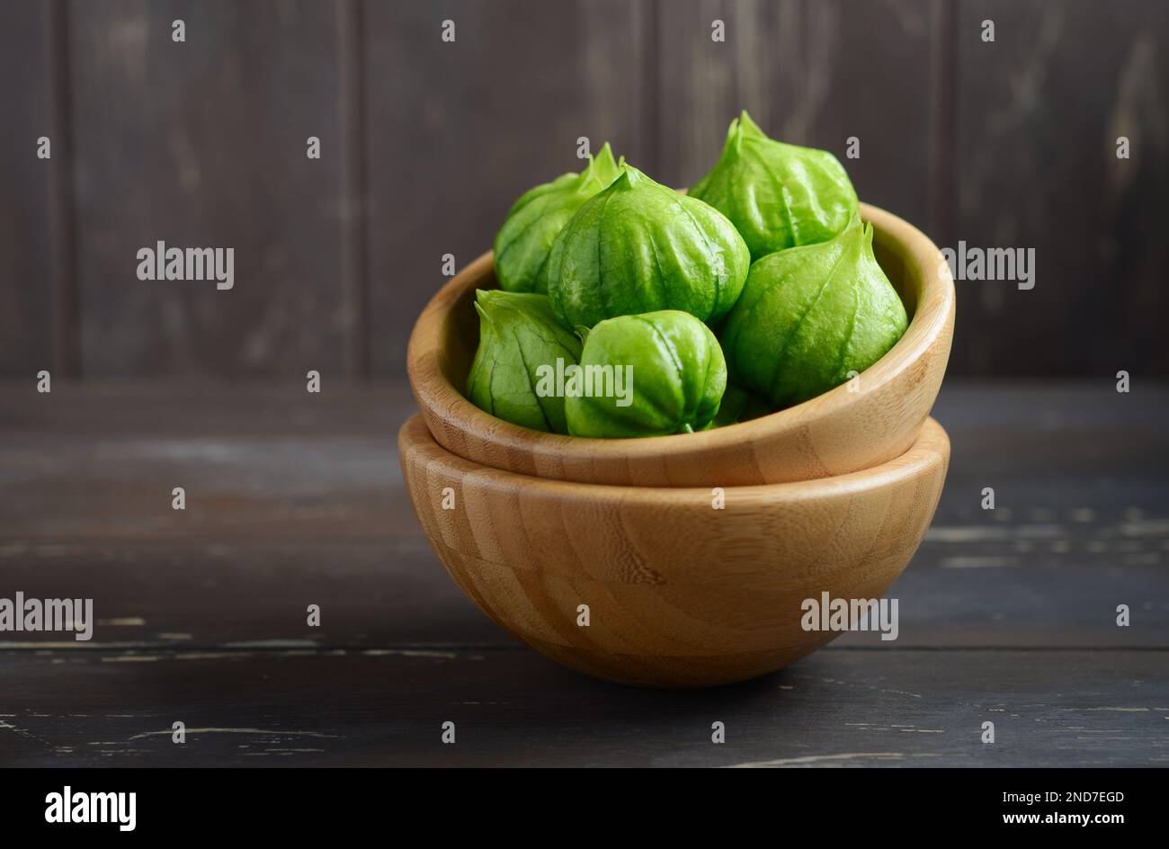 Tomatillos freschi biologici verdi (Physalis philadelphica) con una buccia su un tavolo rustico di legno. Foto Stock