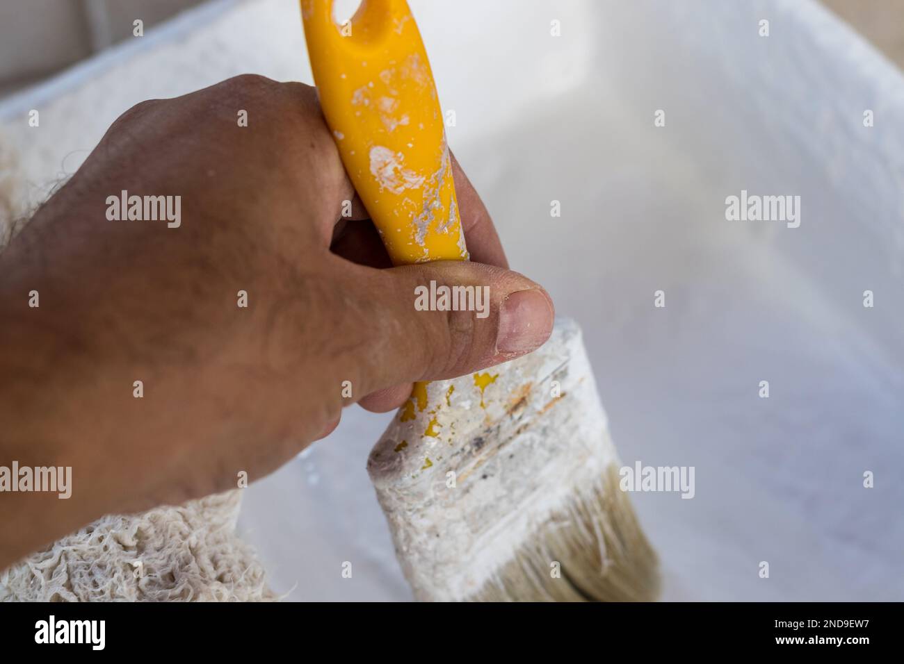 Un uomo che dipinge una parete esterna con un pennello Foto Stock