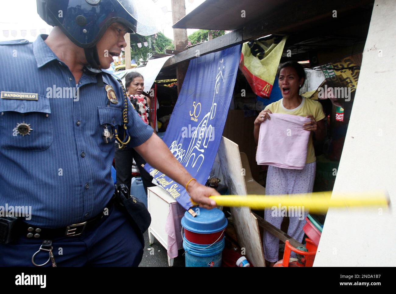 A resident, right, shouts at a police officer as they effect the demolition of shanties at a poor neighborhood at Manila's Quezon city Thursday Aug. 12, 2010 in the Philippines. Hundreds of squatters were forced to abandon their homes after demolition crew , aided by Philippine National Police, tear down their shanties. (AP Photo/Bullit Marquez) Foto Stock