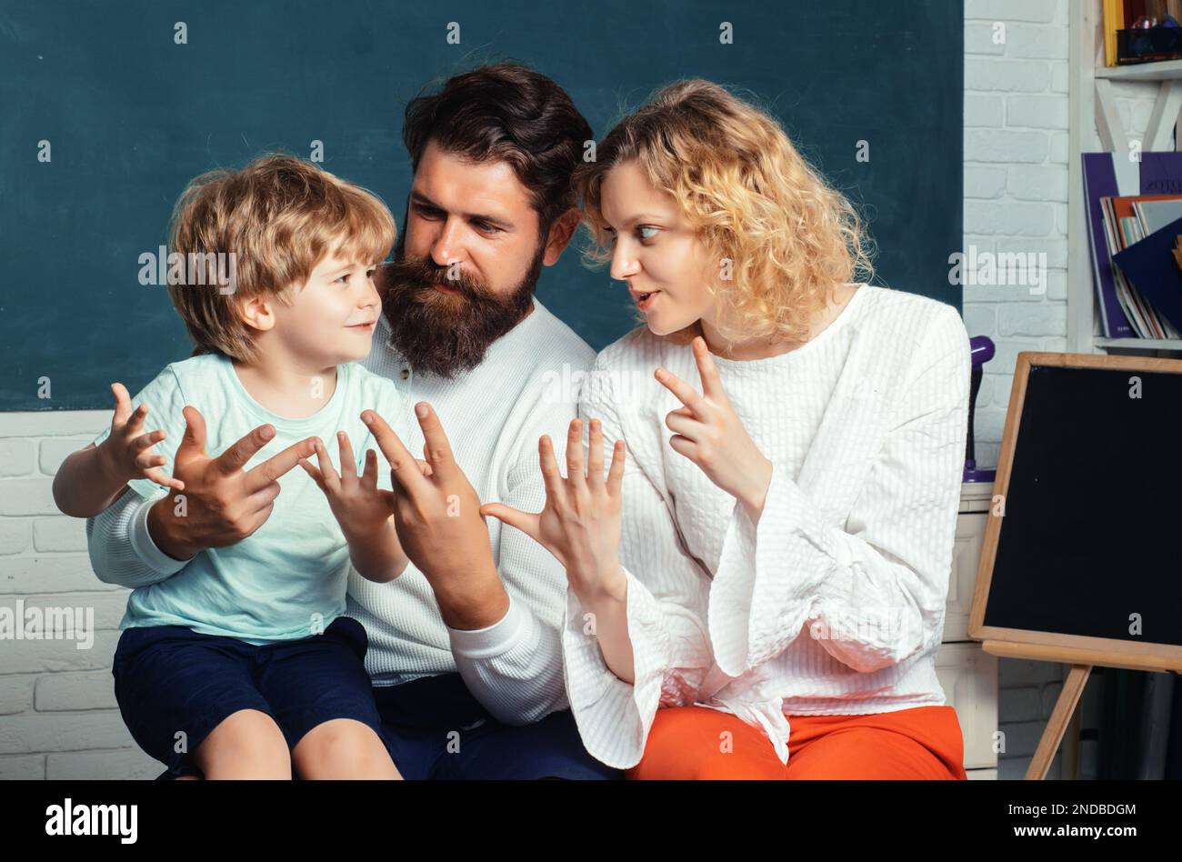 Felice giovane coppia che sta in piedi con il loro figlio alla laurea. Sostenere gli allievi a scuola. Collaborazione con la comunità scolastica. Foto Stock