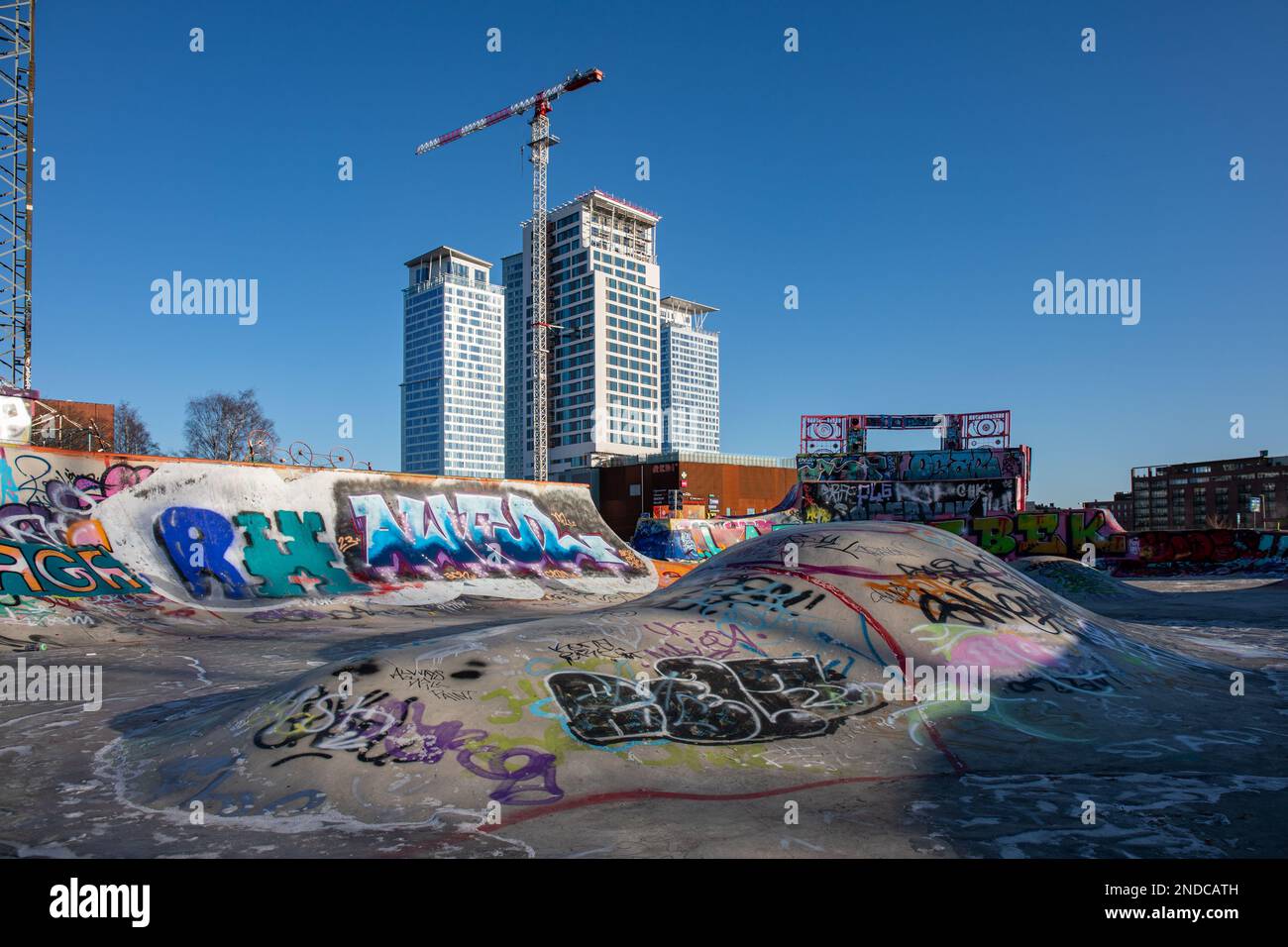 Suvilahti DIY Skatepark con graffiti, alti edifici Kalasatama sullo sfondo, nel quartiere Suvilahti di Helsinki, Finlandia Foto Stock